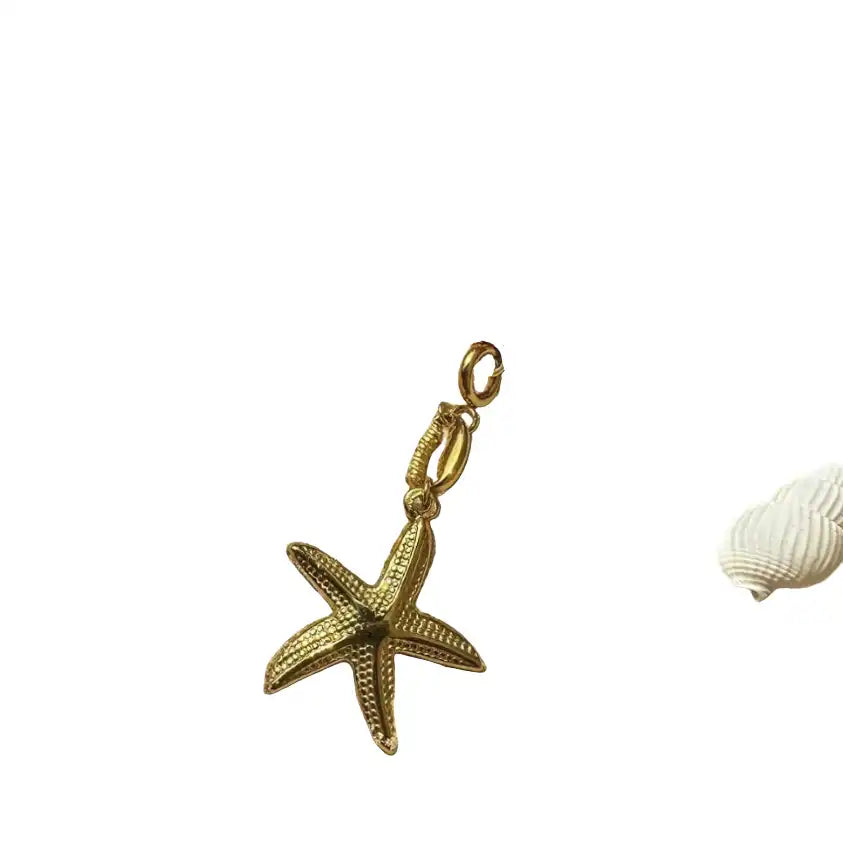 Gold starfish pendant on a white background with a shell.