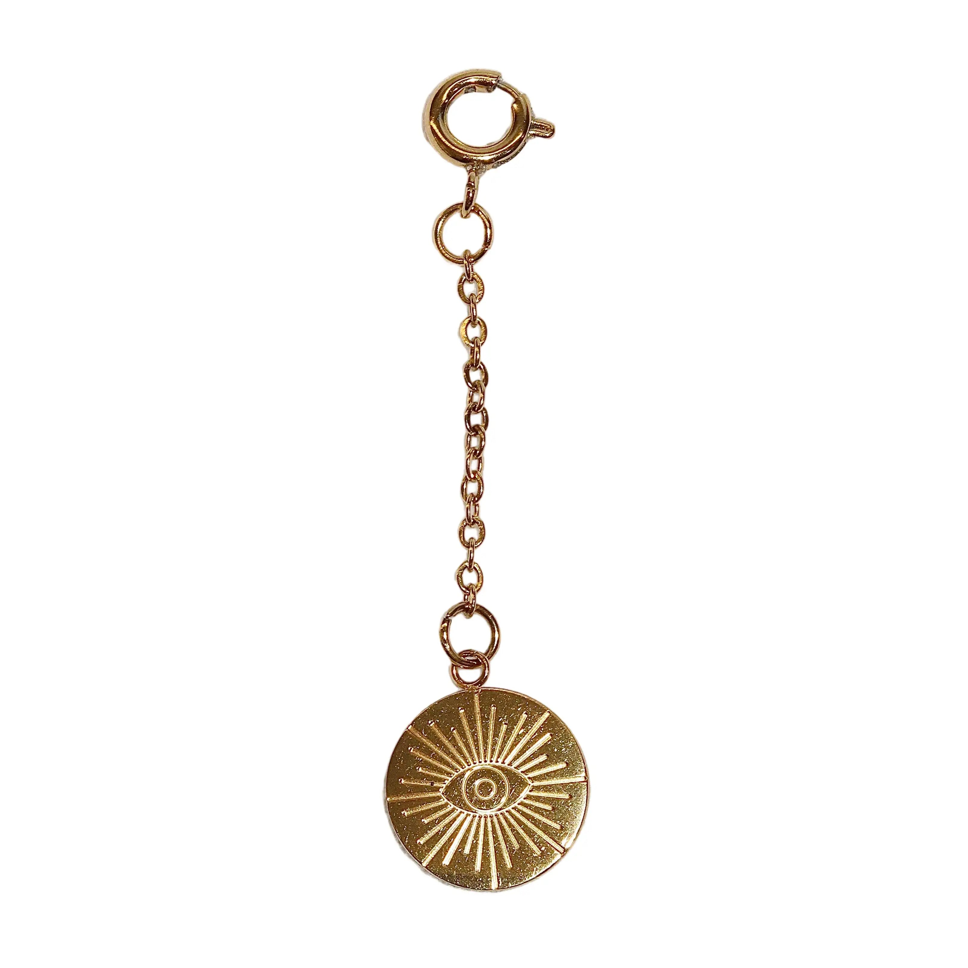 Gold pendant charm with eye design on a white background